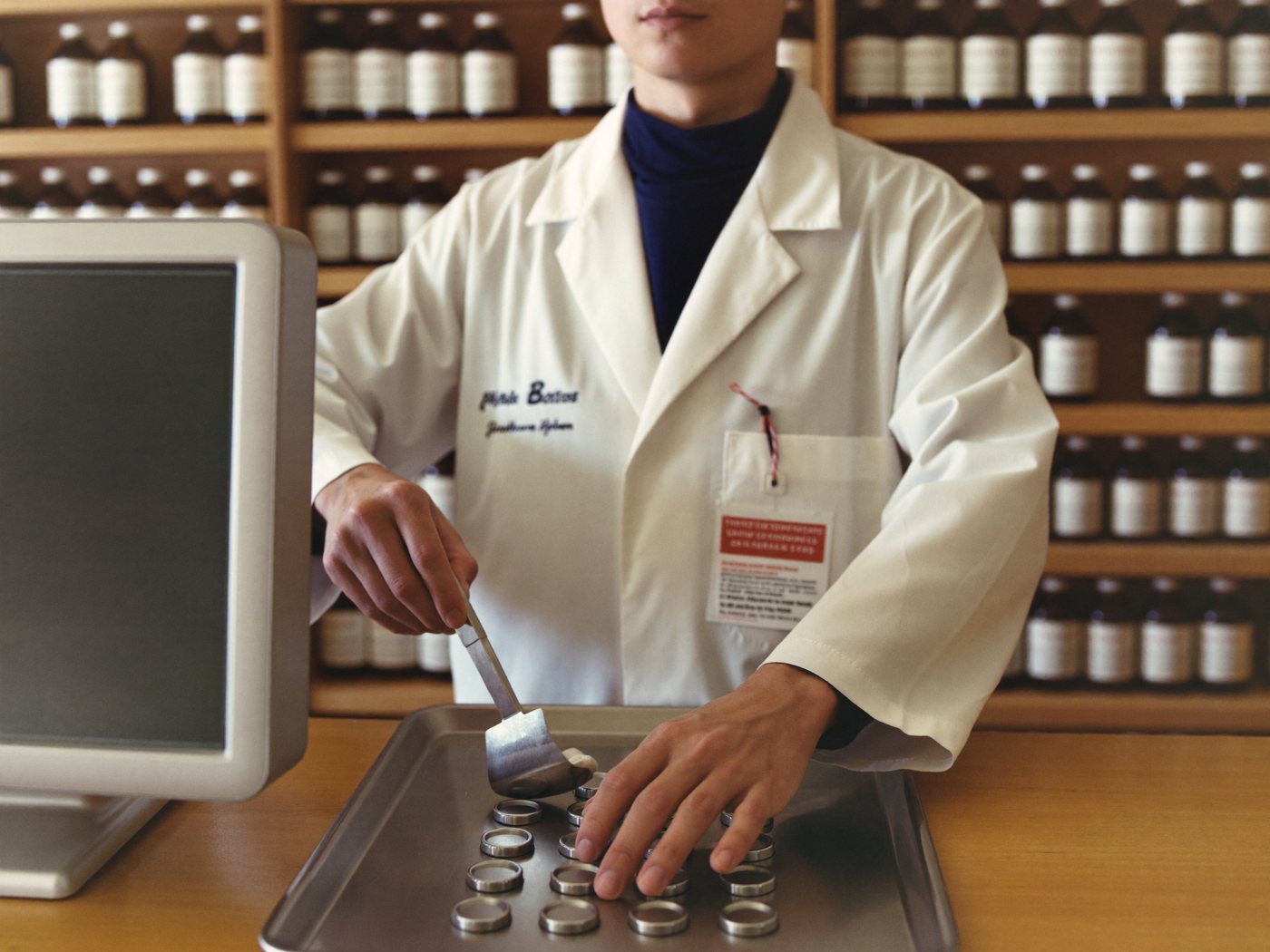 Certified pharmacy technician at work behind a pharmacy counter